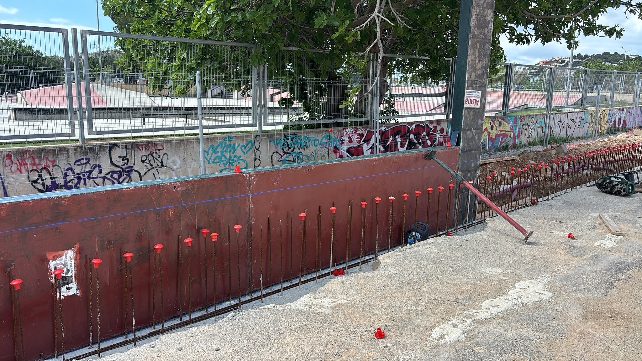 Muro con esperas de ferralla junto a valla de obra